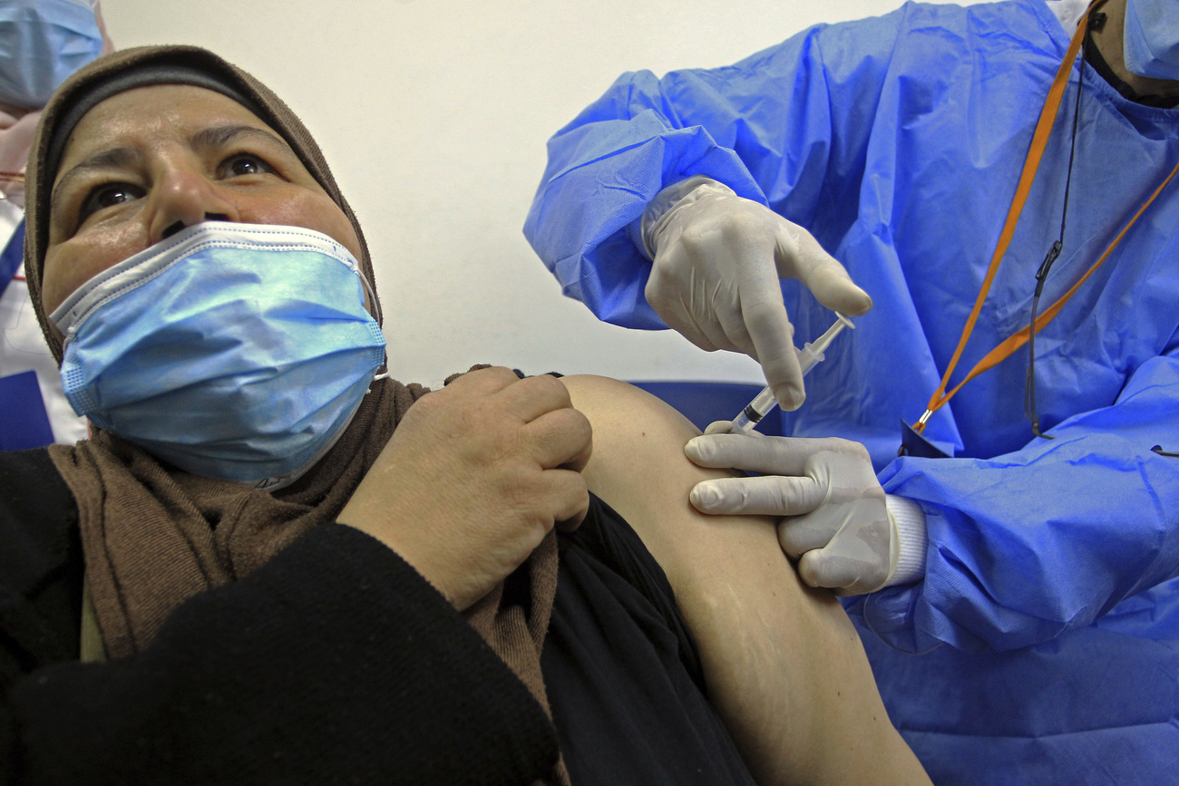 ممرضة تقوم بعملية التطعيم لسيدة