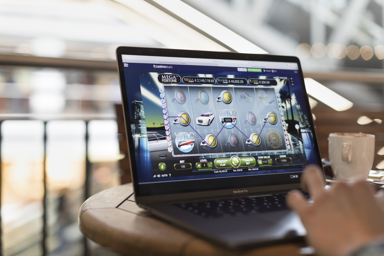 Laptop computer on table with hand of gambler