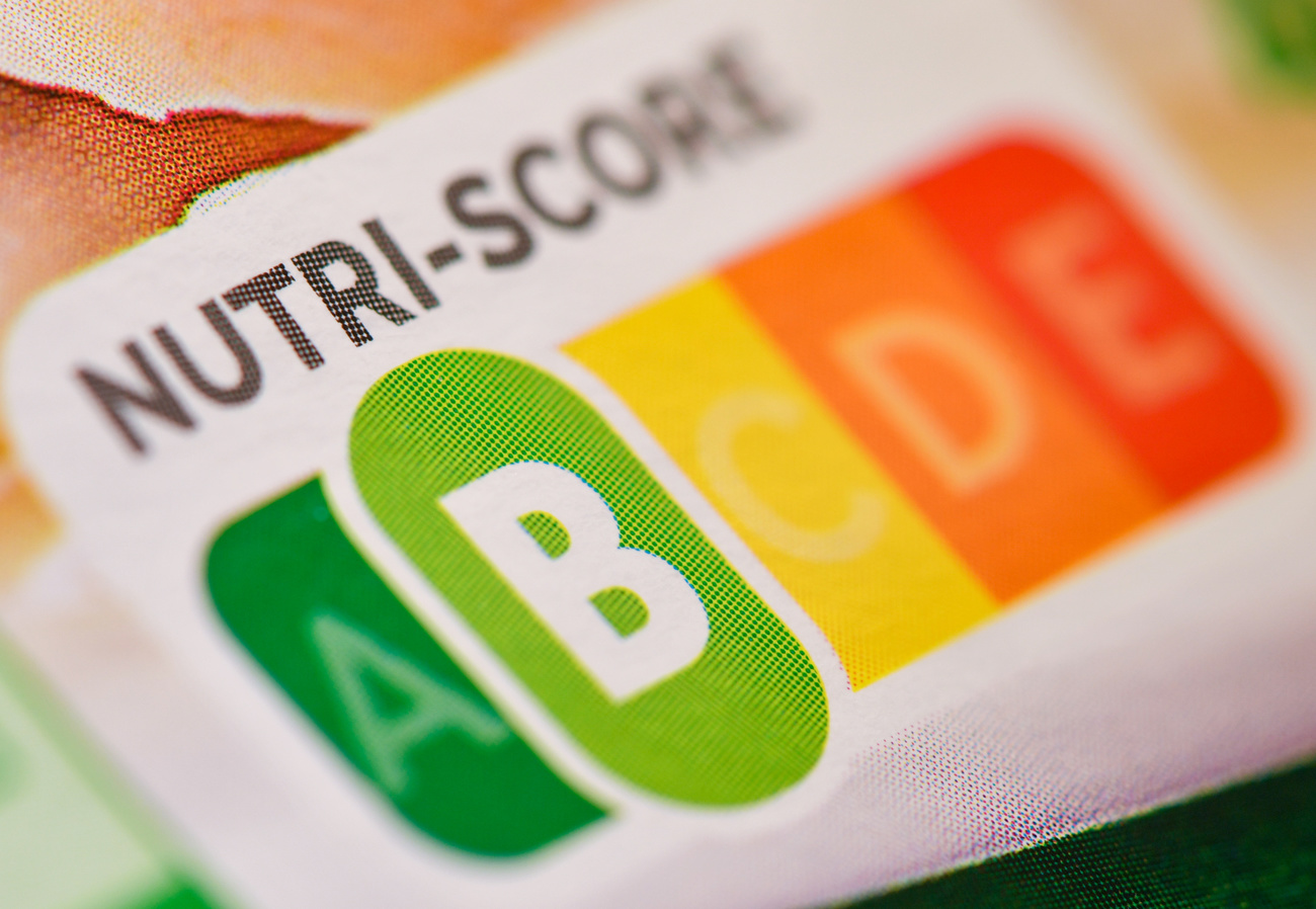 Primo piano di confezione alimentare con riquadro intitolato Nutri-Score e lettere ABCDE (in verde-giallo-rosso) B in evidenza