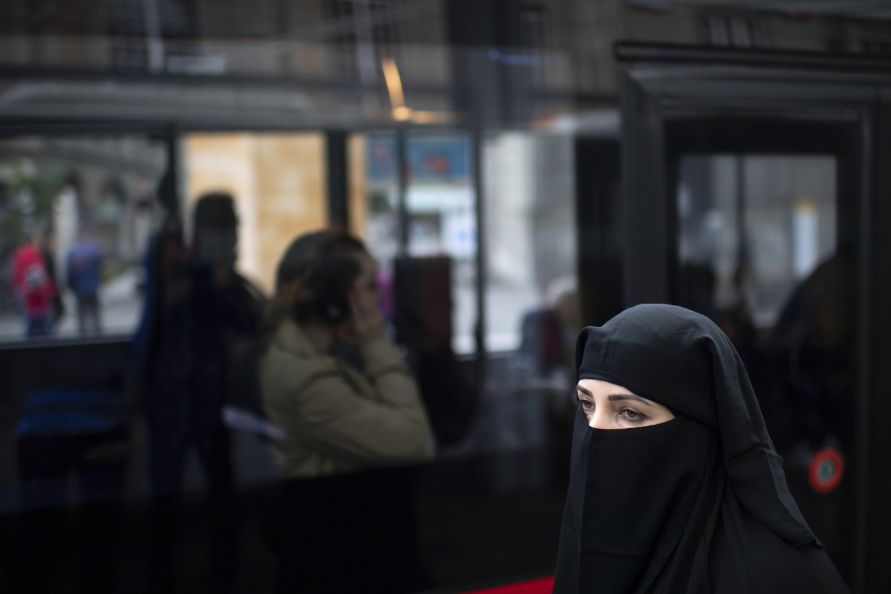 امرأة ترتدي البرقع الأسود تجلس في وسائل النقل العام