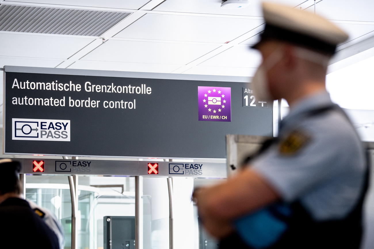 Controllo doganale di aeroporto con insegne in tedesco; in primo piano, sfocato, agente in divisa