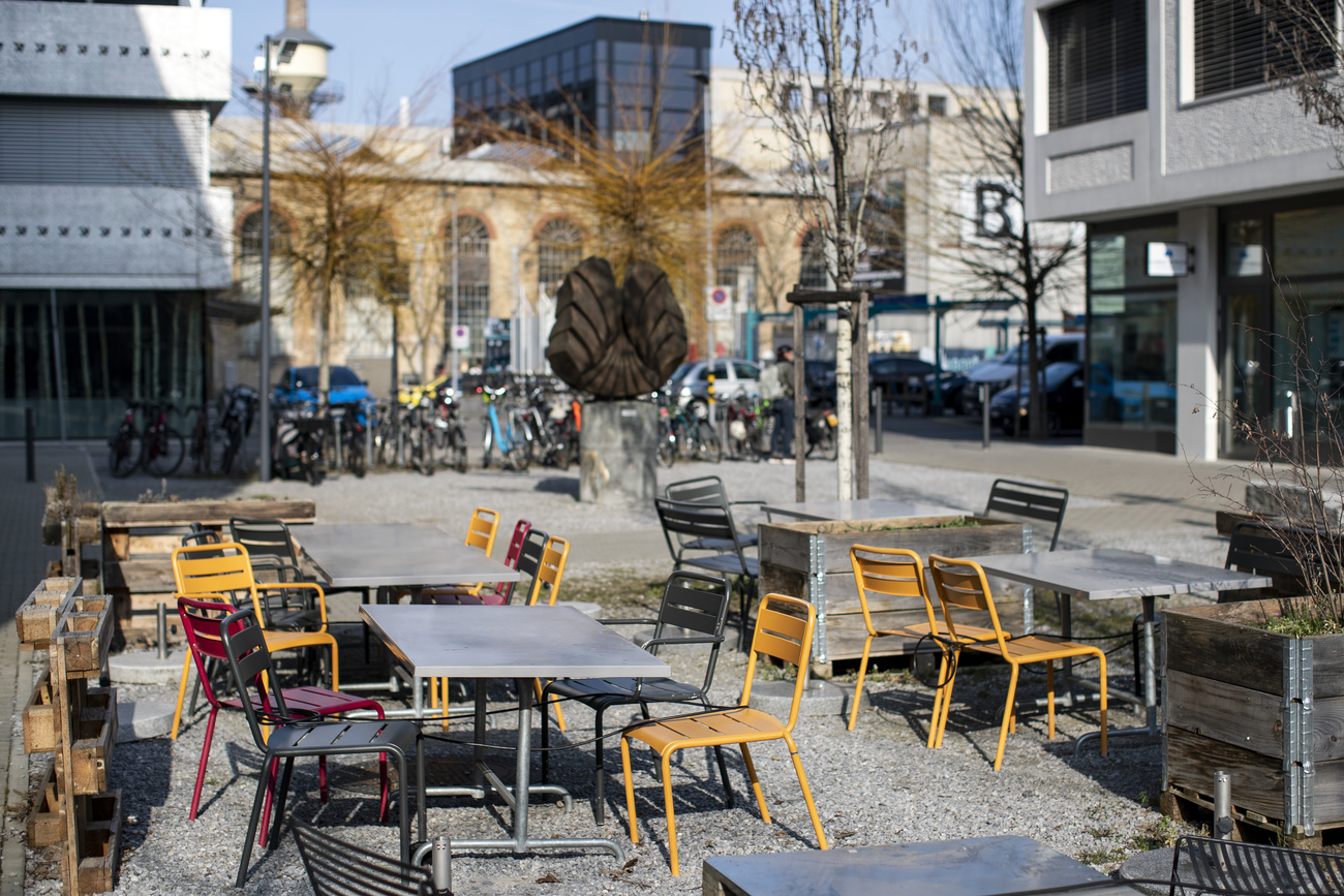 Déhors di un bar con tavolini e sedie ma completamente vuoto in ambiente urbano