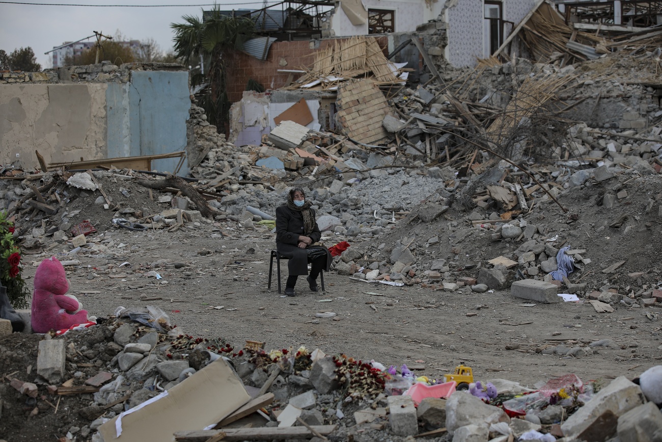 Eine Frau sitzt inmitten von Trümmern