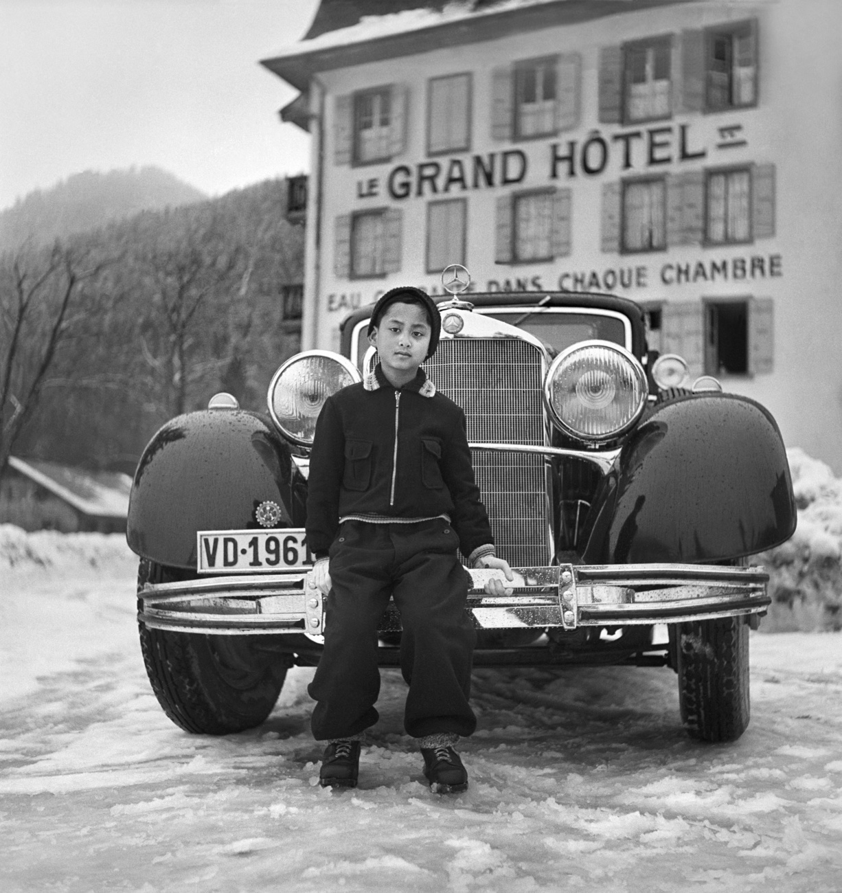 bambino davanti a un auto di lusso