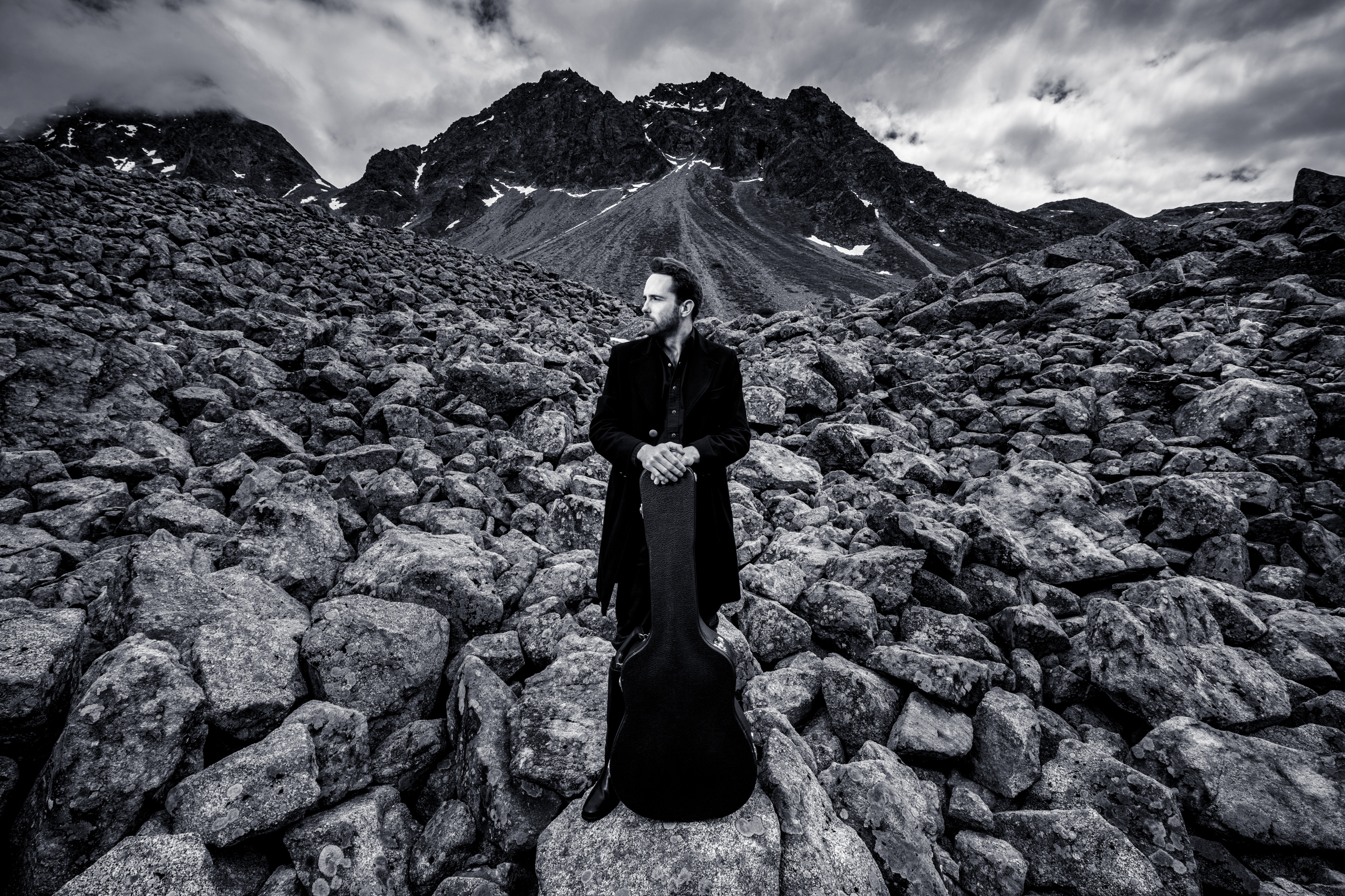 Florian Fox in front of a mountain with his guitar