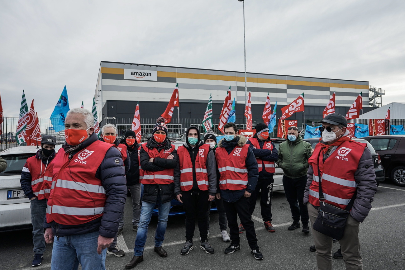 persone brandiscono delle bandiere davanti a uno stabilimento