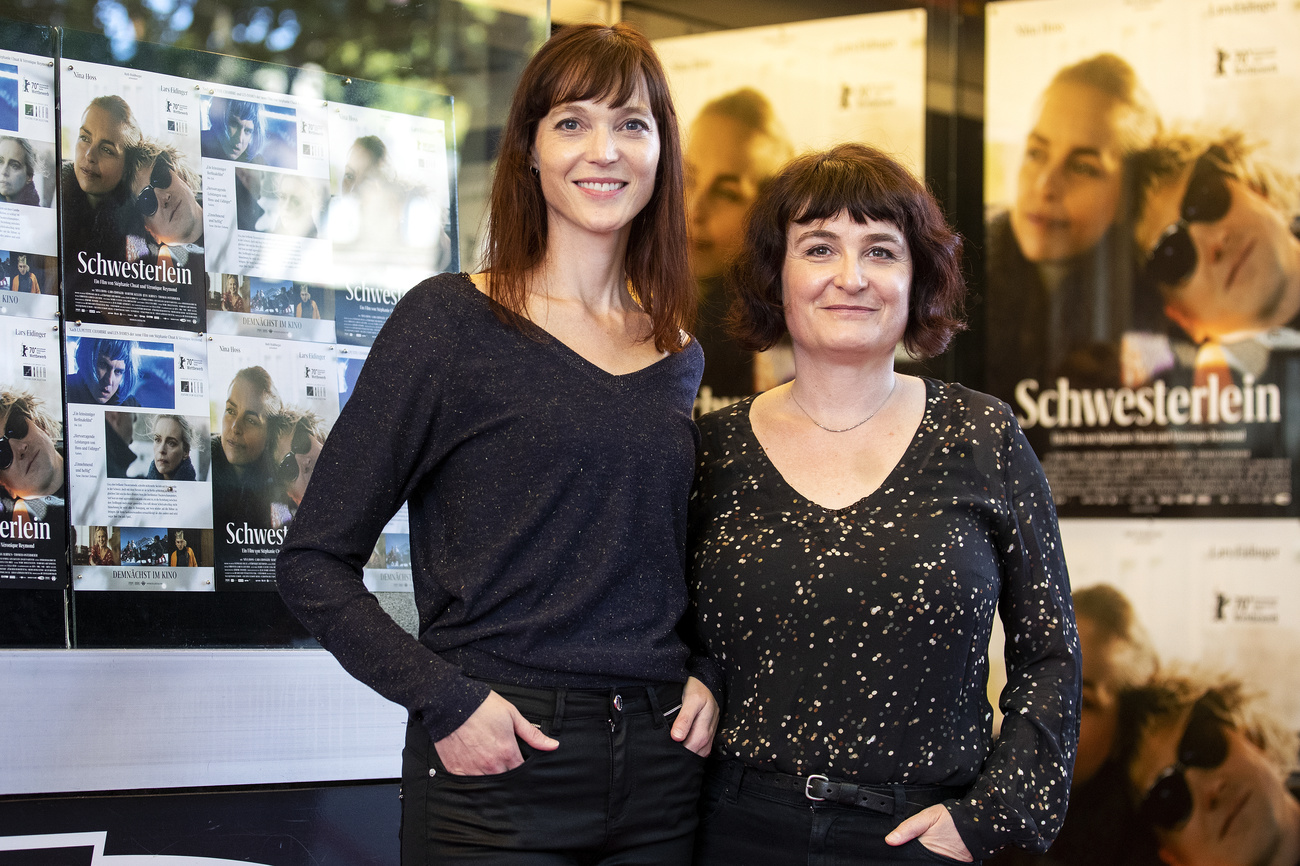 Two women in front of a movie poster