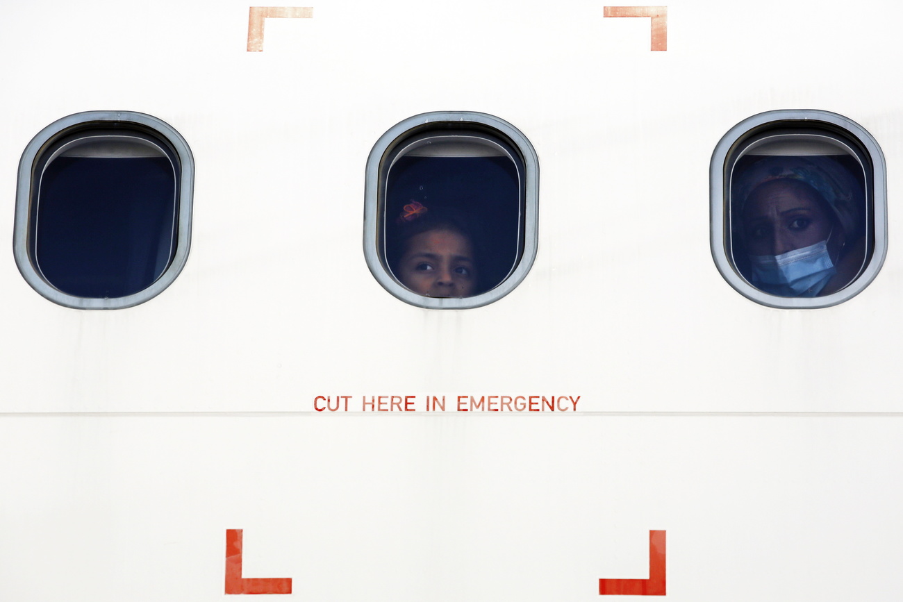 Refugees look out of an airplane window
