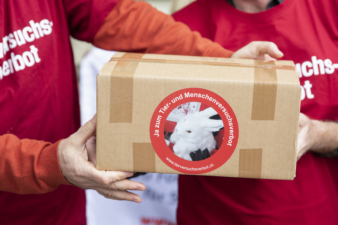 Due persone con maglietta rossa si passano un pacco con logo Tier- und Menschenversuchsverbot