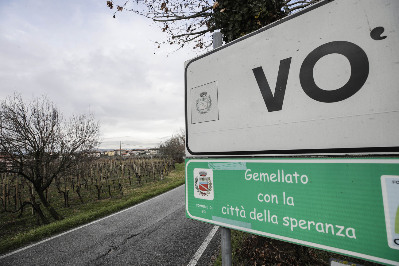 Primo piano del cartello stradale con il nome del comune Vo ; si intravvedono campi e vigneti