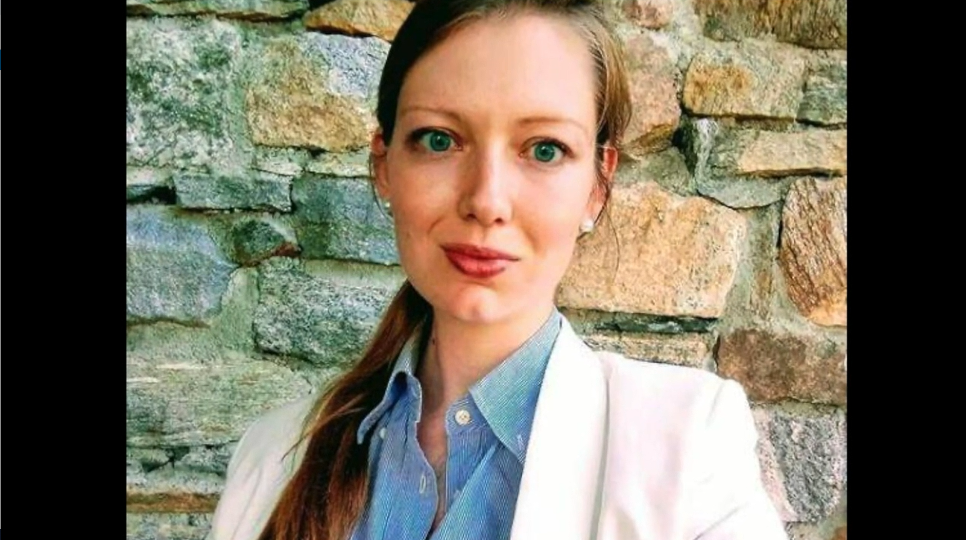 Ritratto di donna con capelli raccolti, occhi chiari, camicia azzurra sotto blazer bianco