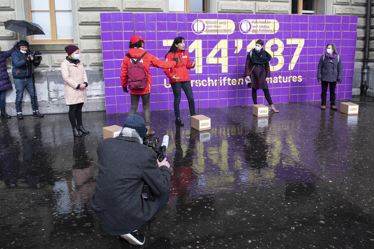 People posing in front of purple boxes containing several thousands of signatures raised for their petition