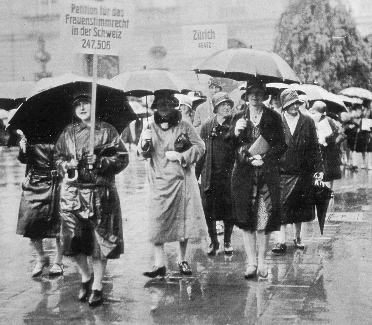 Un grupo de mujeres con paraguas se disponen a presentar una petición