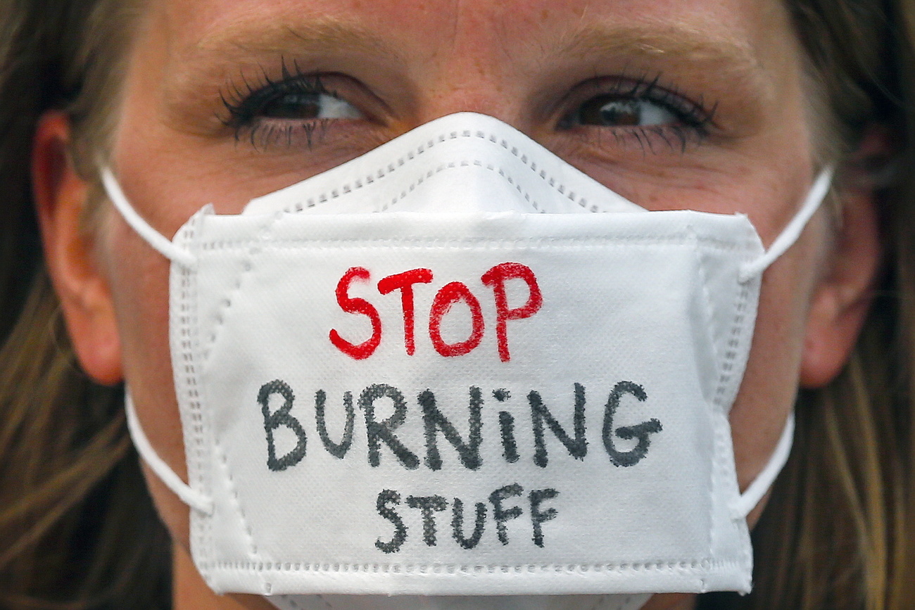 climate change protester with mask that reads stop burning stuff