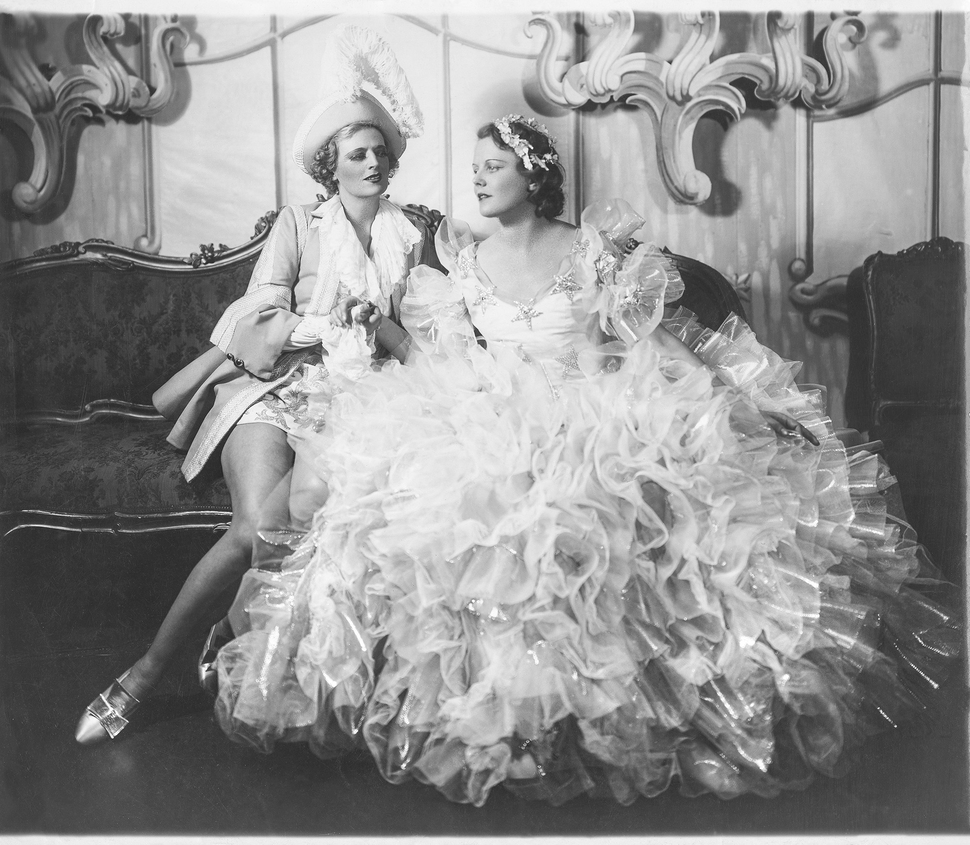 Dos mujeres sentadas en un sofá, uno con vestido de fiesta