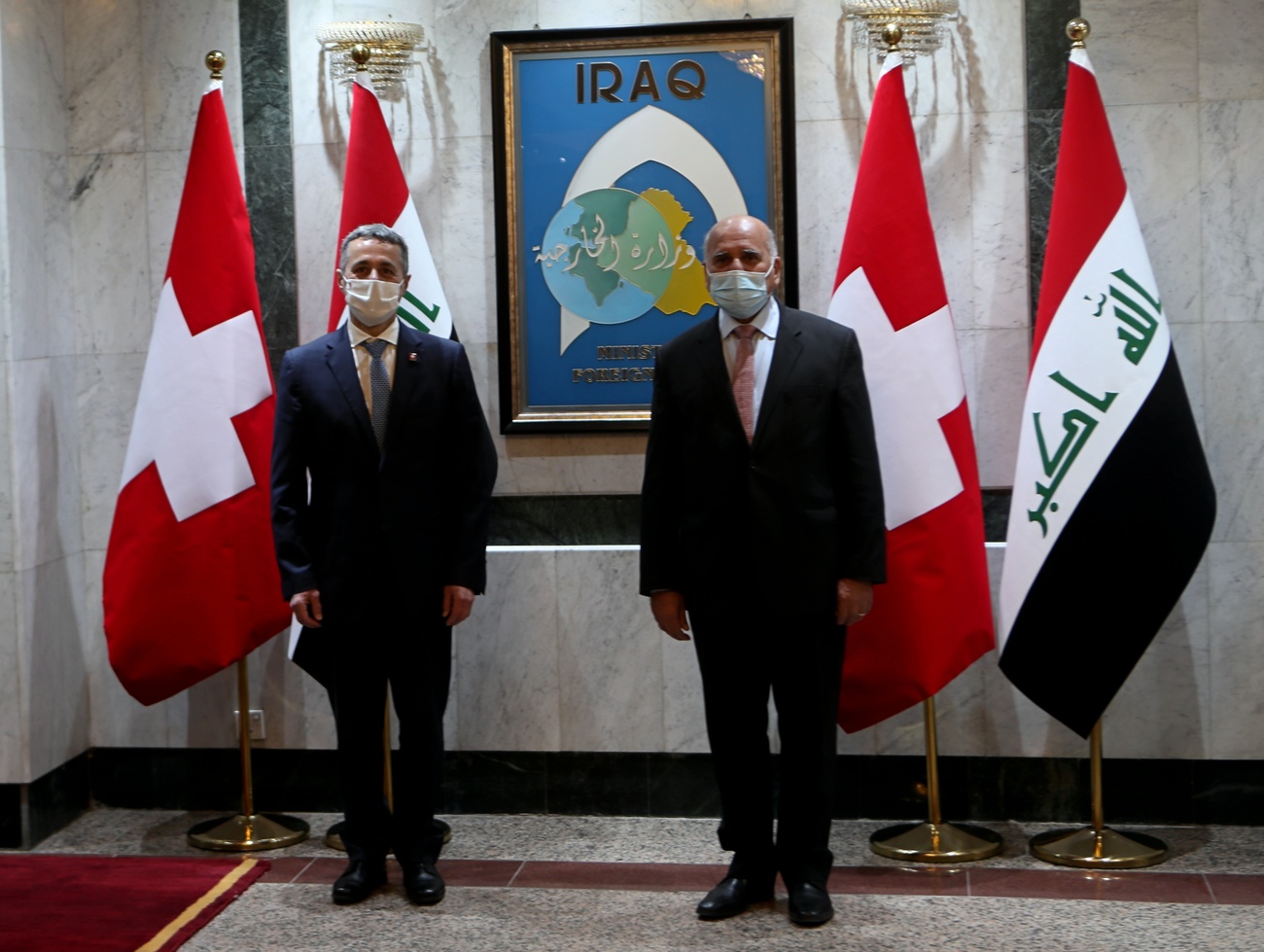 Two masked men in front of flags