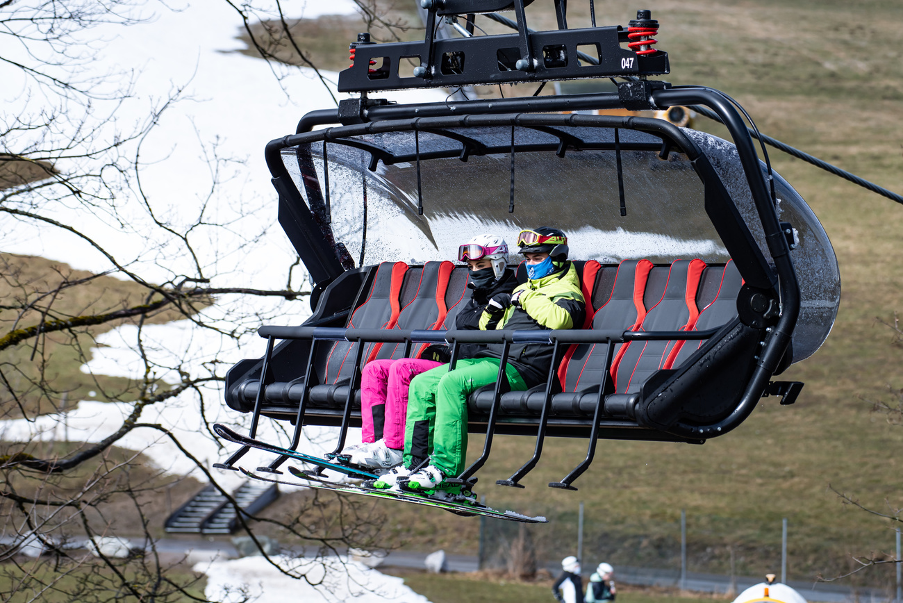 Seggiovia con due sciatori a bordo mentre sulle piste da sci manca la neve.