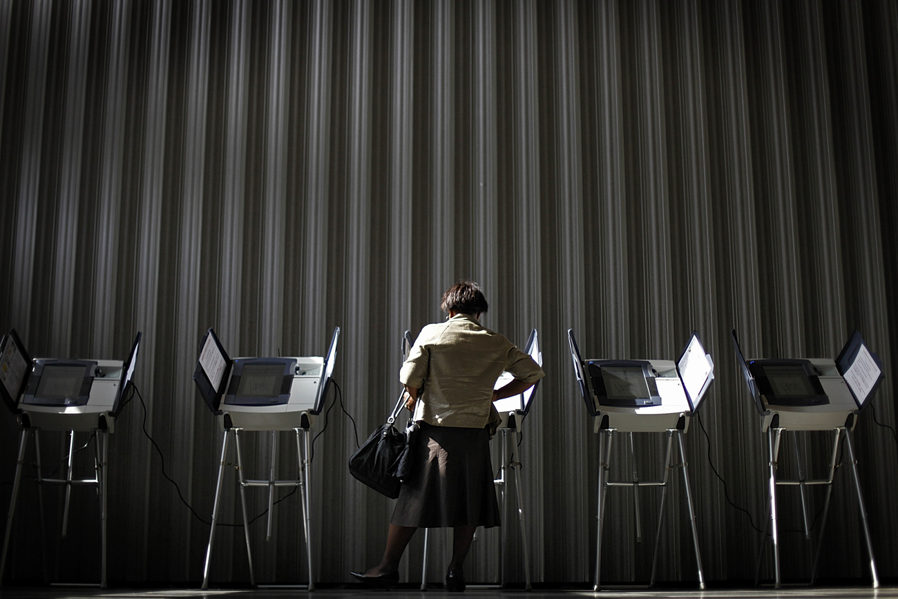 A woman voting at a ballot box.