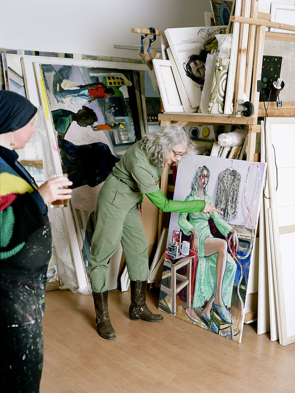 Donna sulla cinquantina mostra a un altra un dipinto che la ritrae posto su un cavalletto