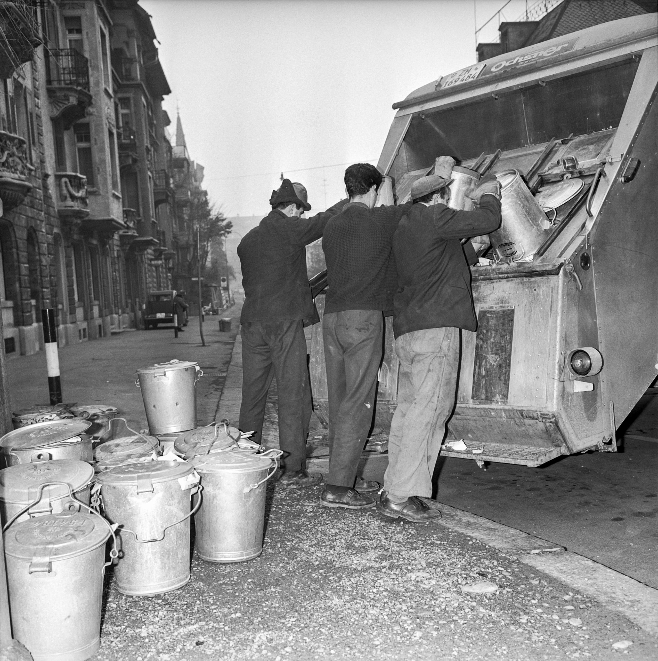 Trabajadores vacían cubos de basura en un camión.