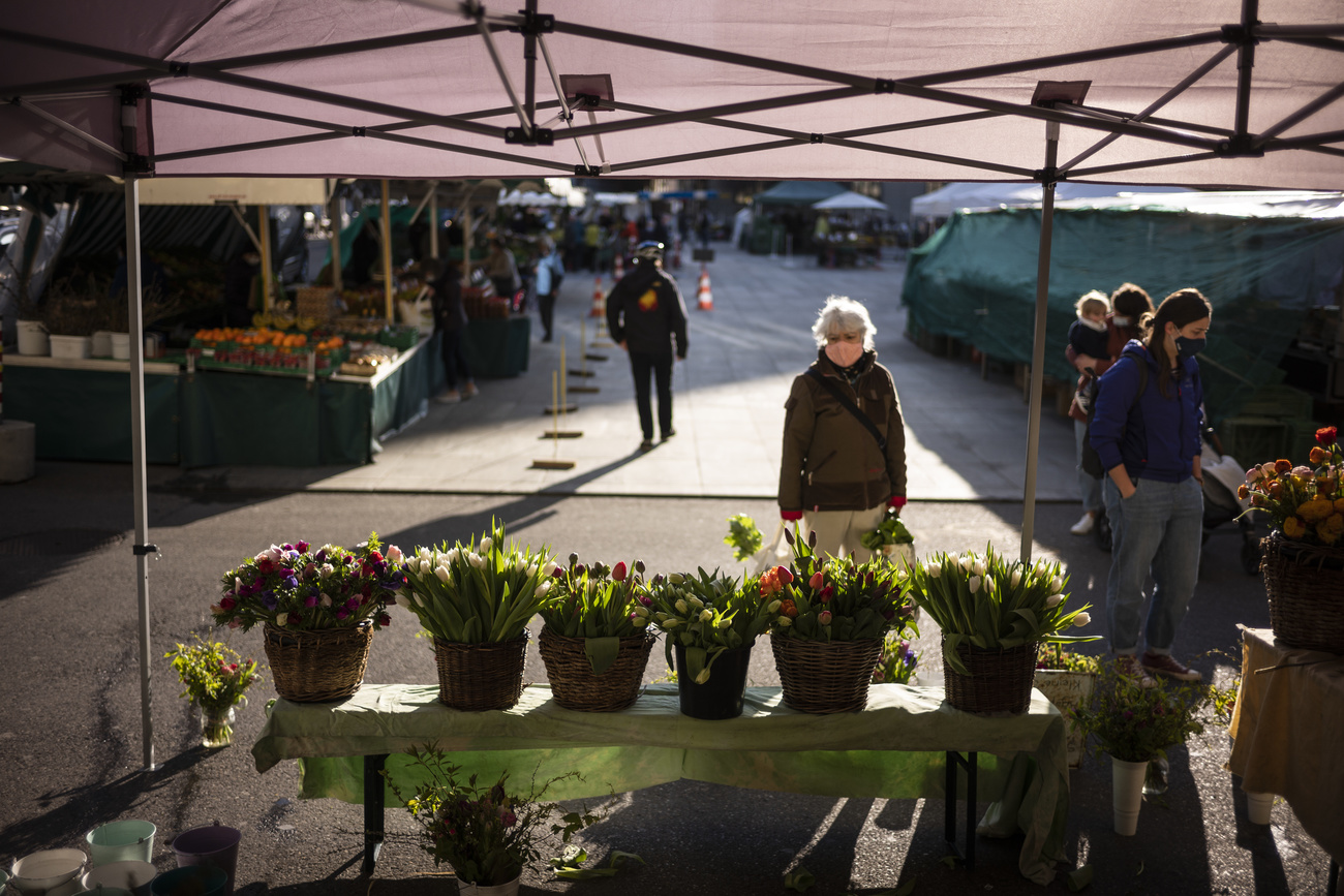 femme masquée devant des fleurs au marché
