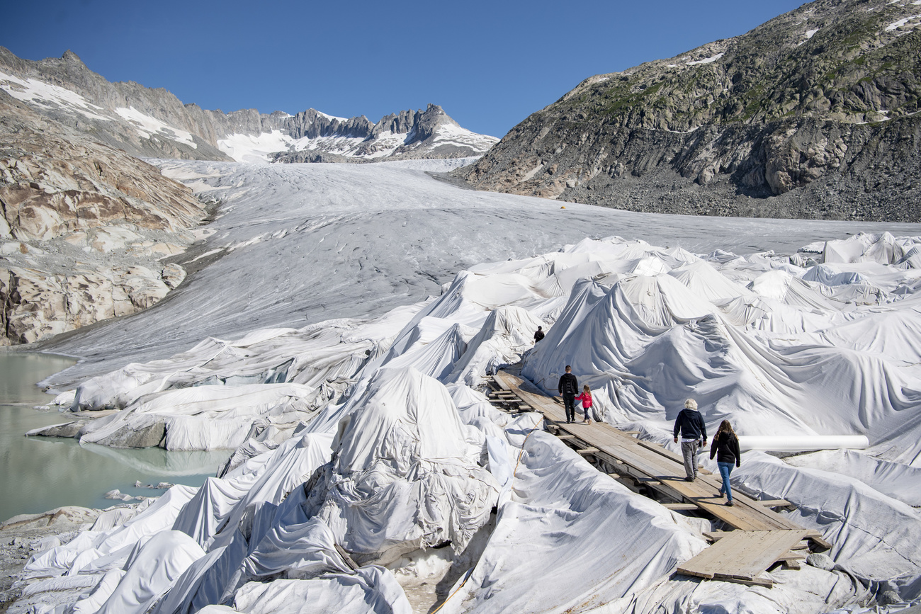 Tarpaulins covering part of a glacier, and people walking across them.