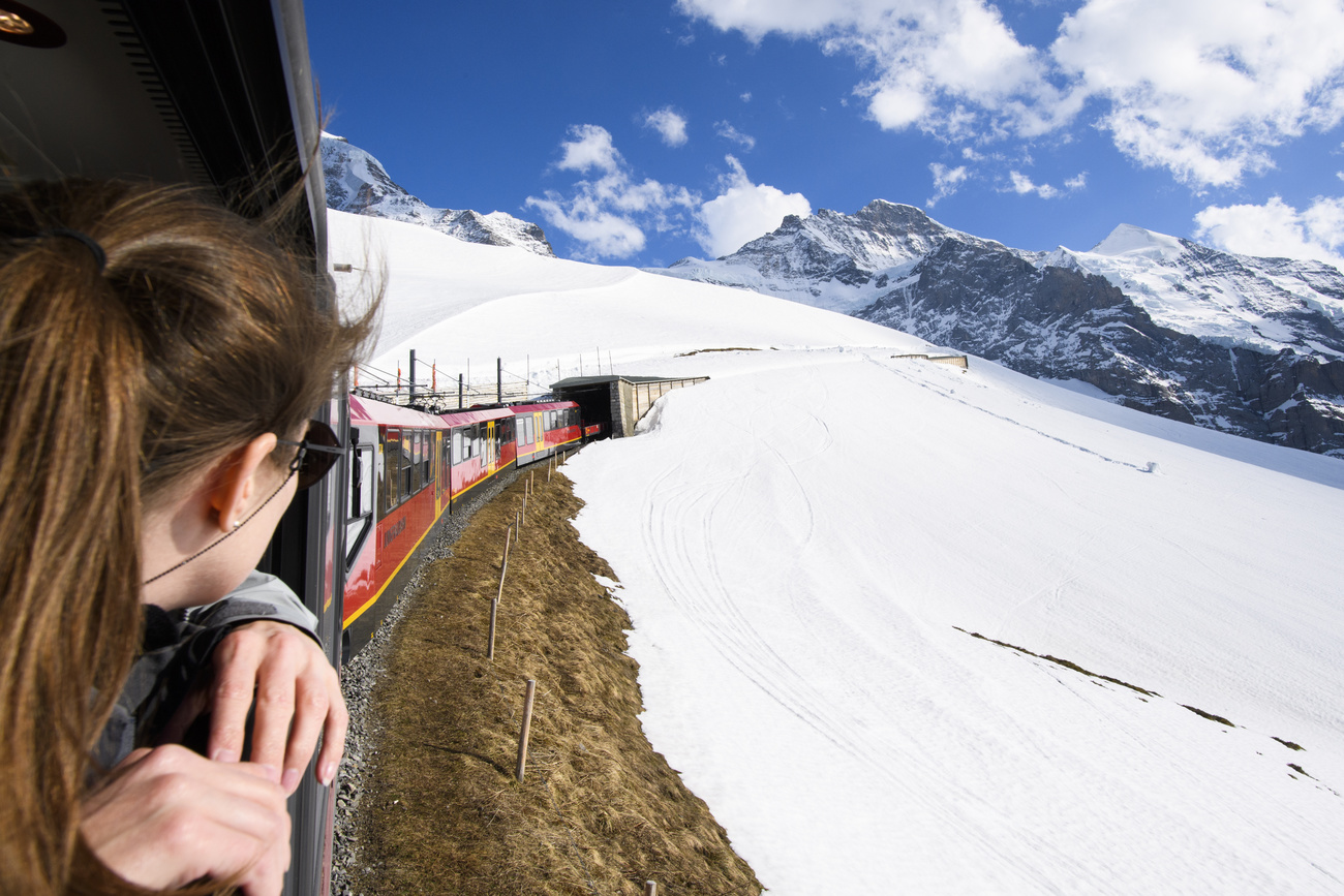 Ragazza guarda dal finestrino coda del treno sul quale sta viaggiando in paesaggio alpino innevato