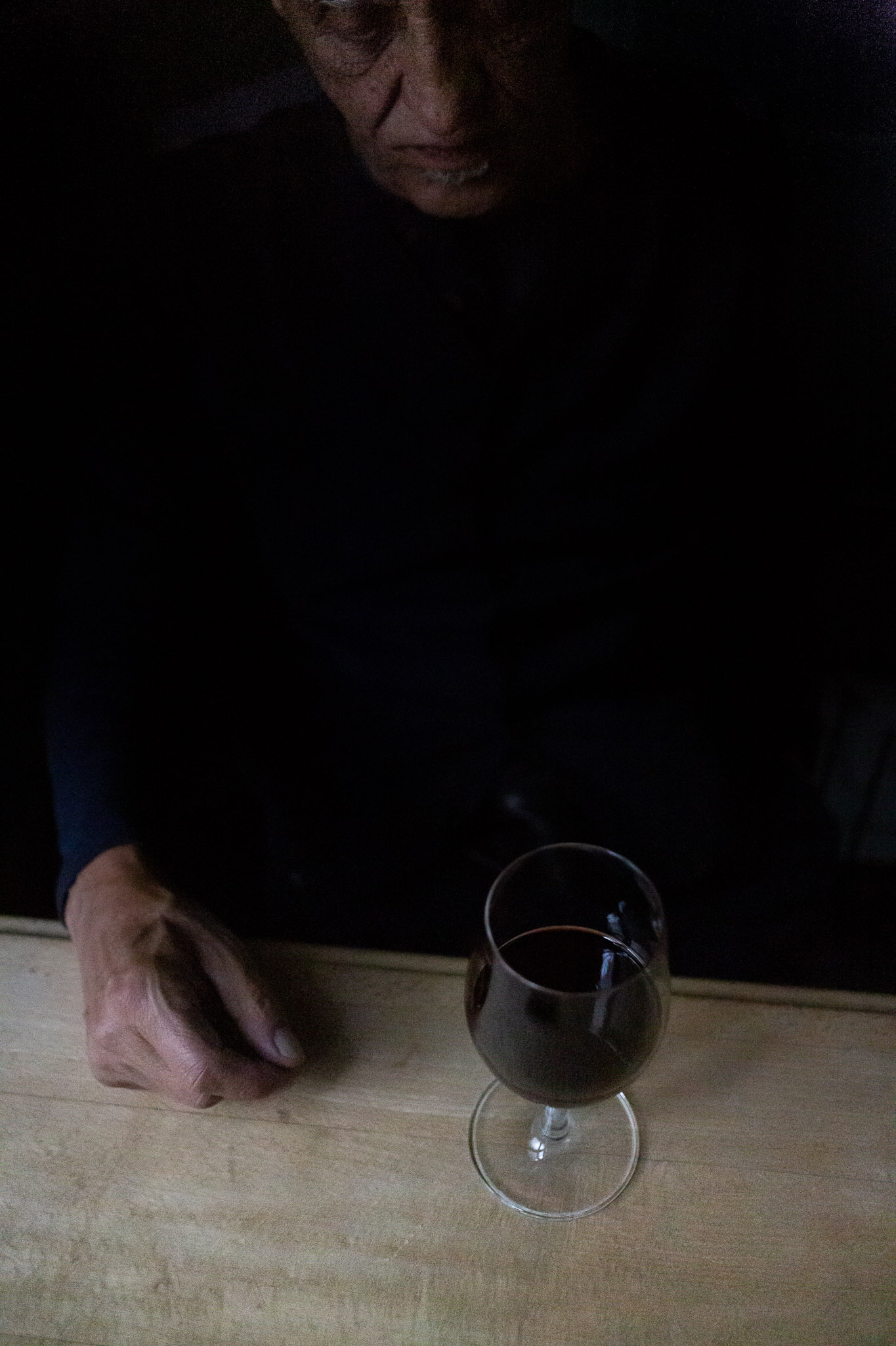 Hombre mayor delante de una copa de vino