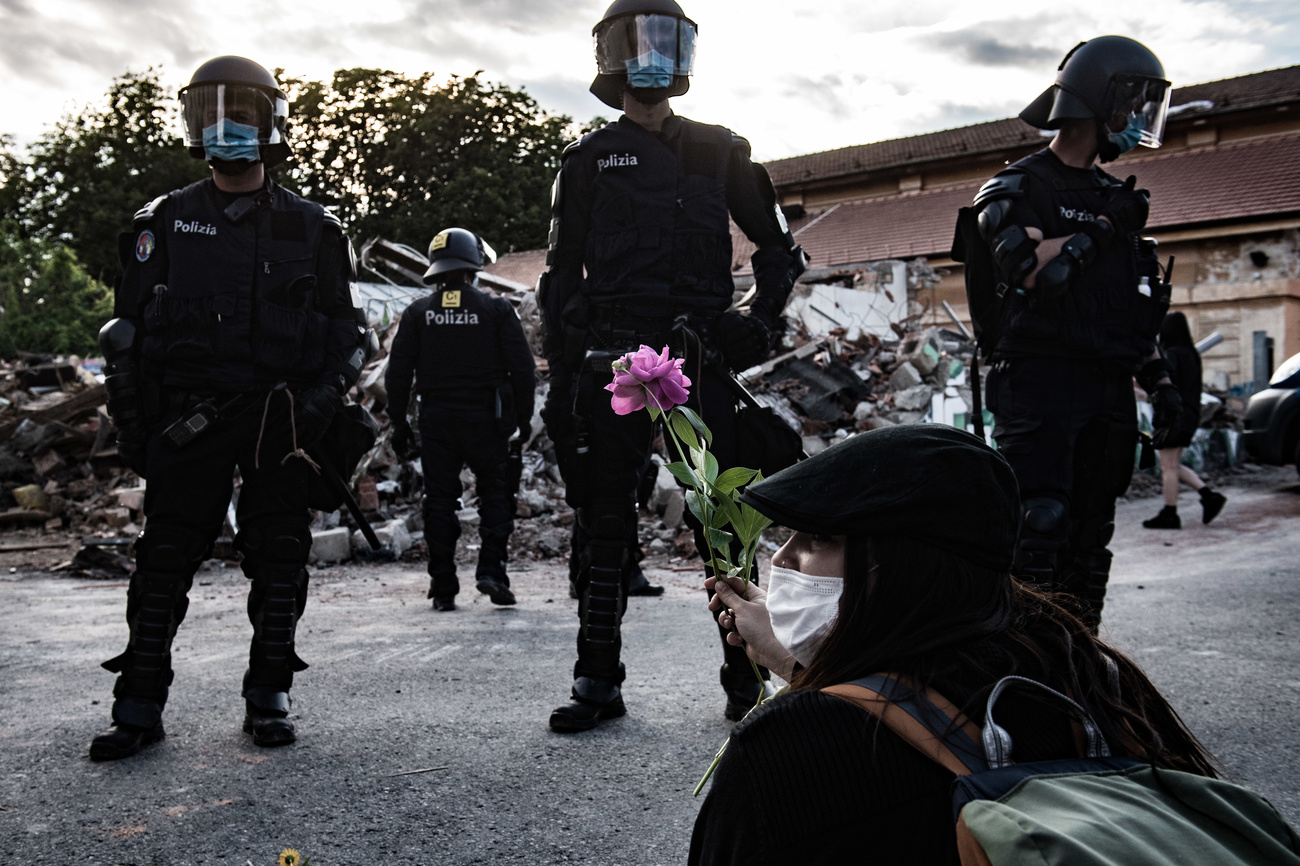 Una sostenitrice del centro autogestito porge un fiore alla polizia davanti alla struttura distrutta.