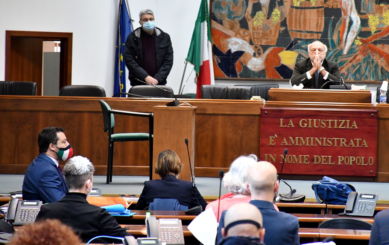 Aula di tribunale con giudice a mani conserte e Salvini di profilo; Bongiorno di schiena