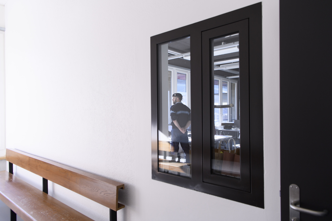 Security guard at an asylum centre seen through a window