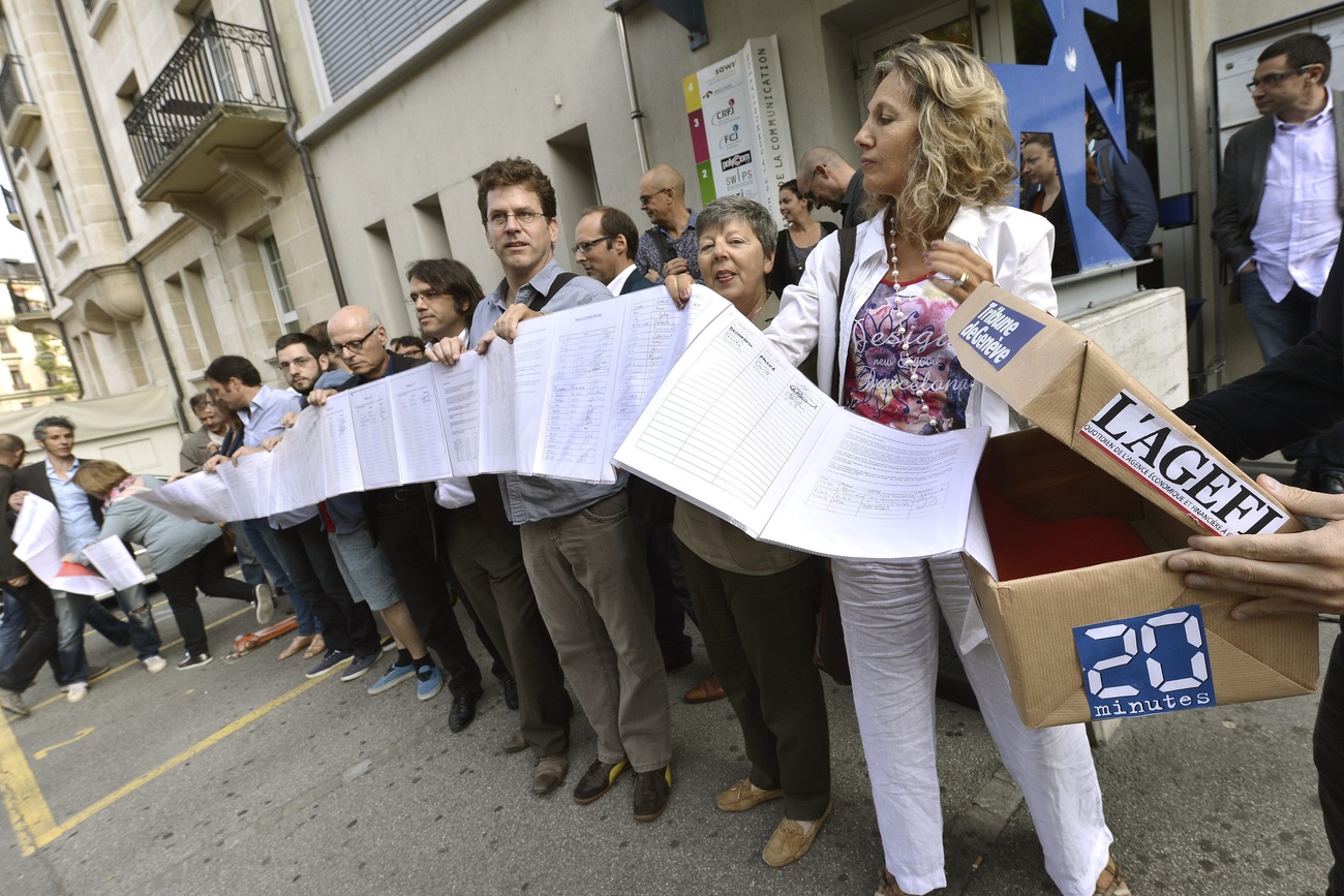 String of people holding up several pages of signatures they raised for their petition.