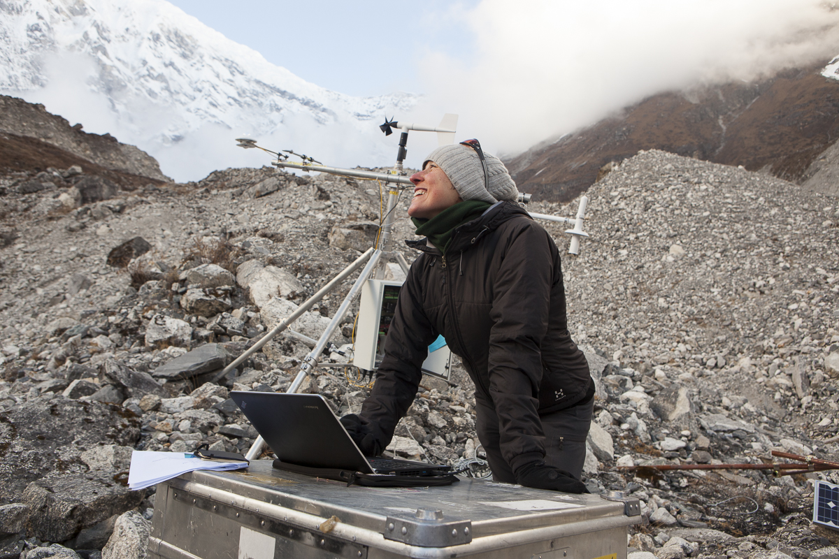 Mujer con una computadora y, al fondo, un glaciar