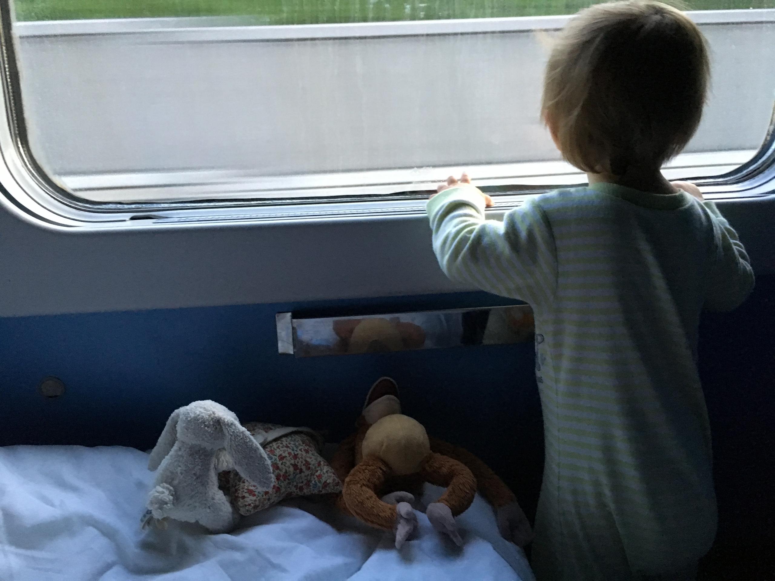 Una niña pequeña mira a través de la ventana de un tren.