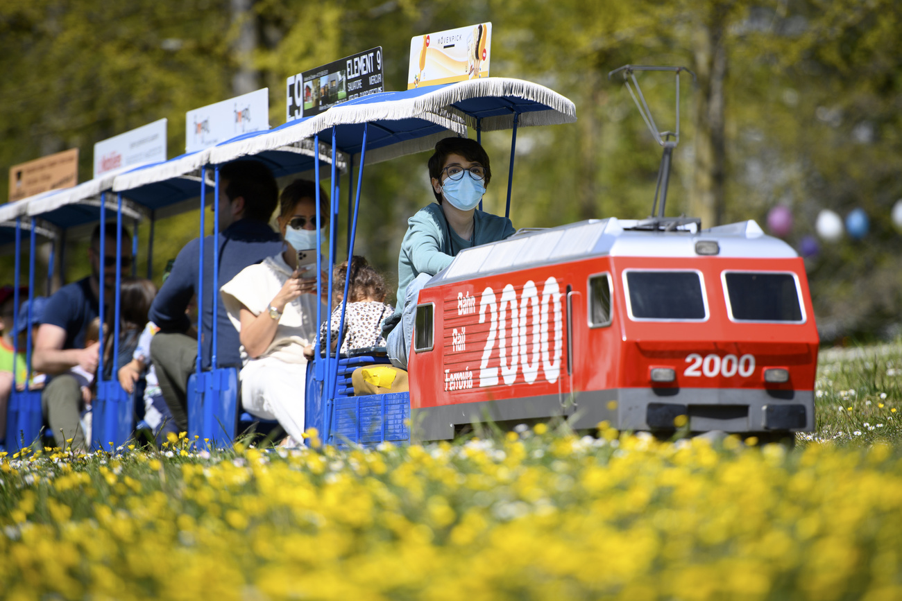 people on a miniature train in Switzerland wear masks