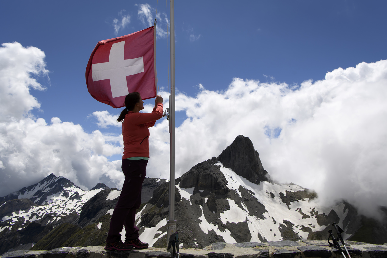 Un hombre con una bandera de Suiza en una montaña