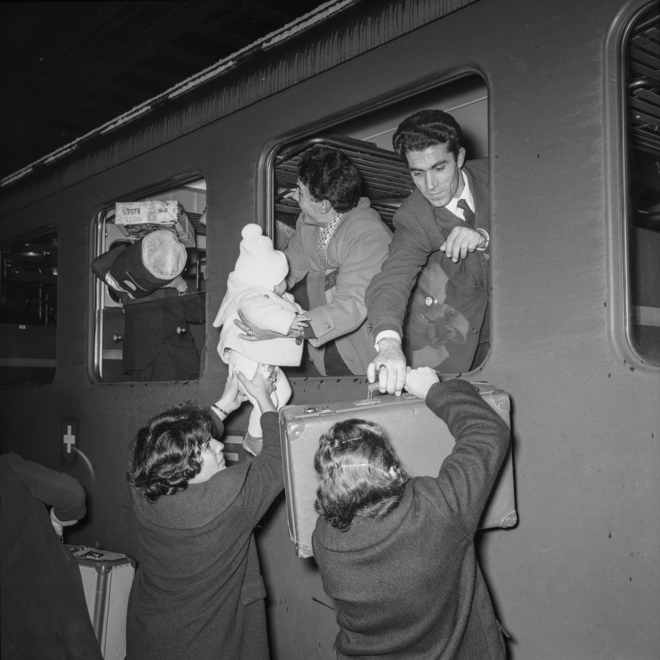 Personas en el andén y viajeros se saludan a través de la ventanilla de un vagón de ferrocarril