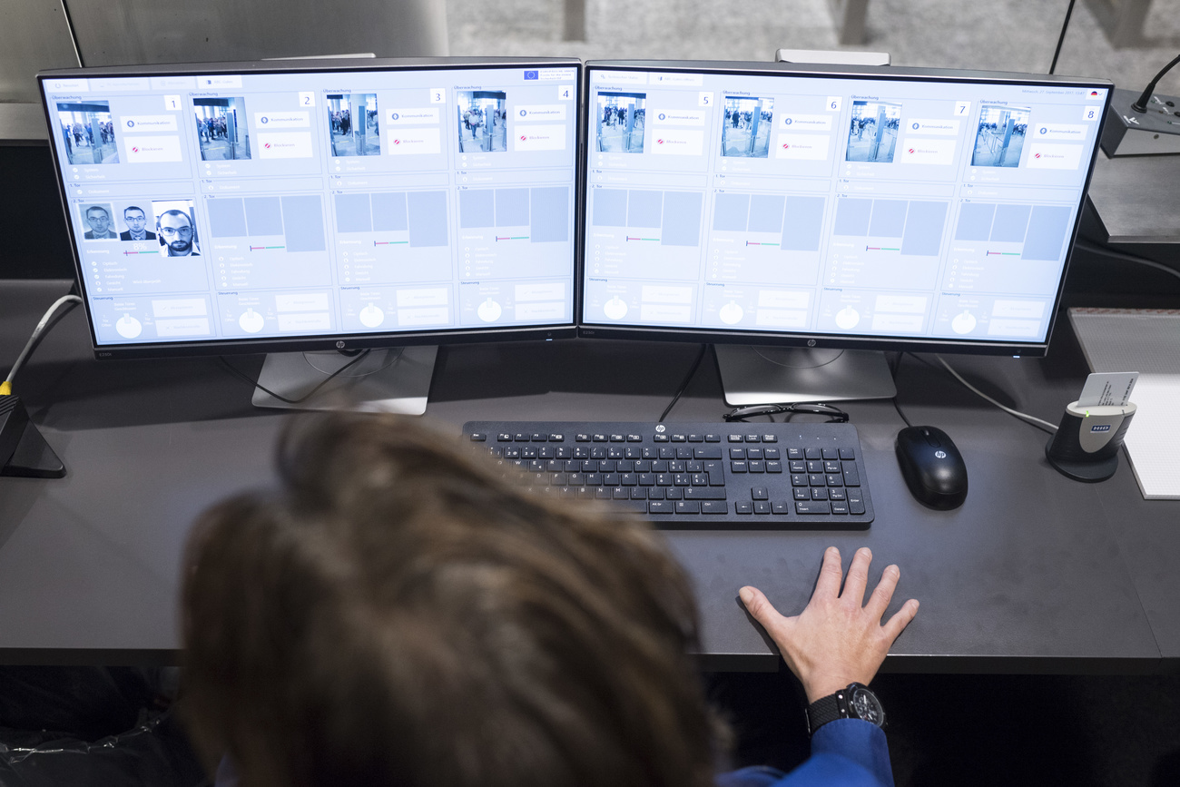 Customs officer in front of two computer screens showing details of passport