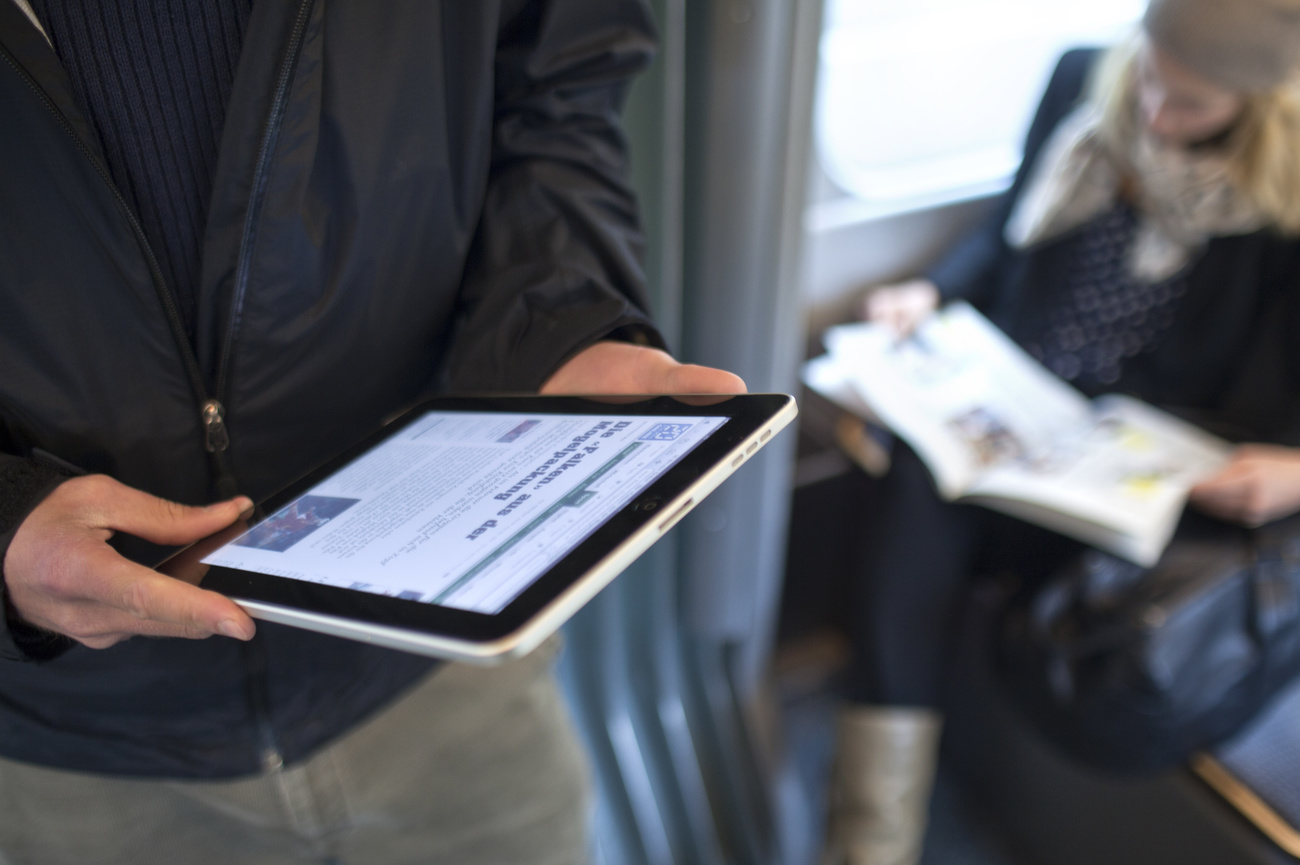 Man reading iPad in train.
