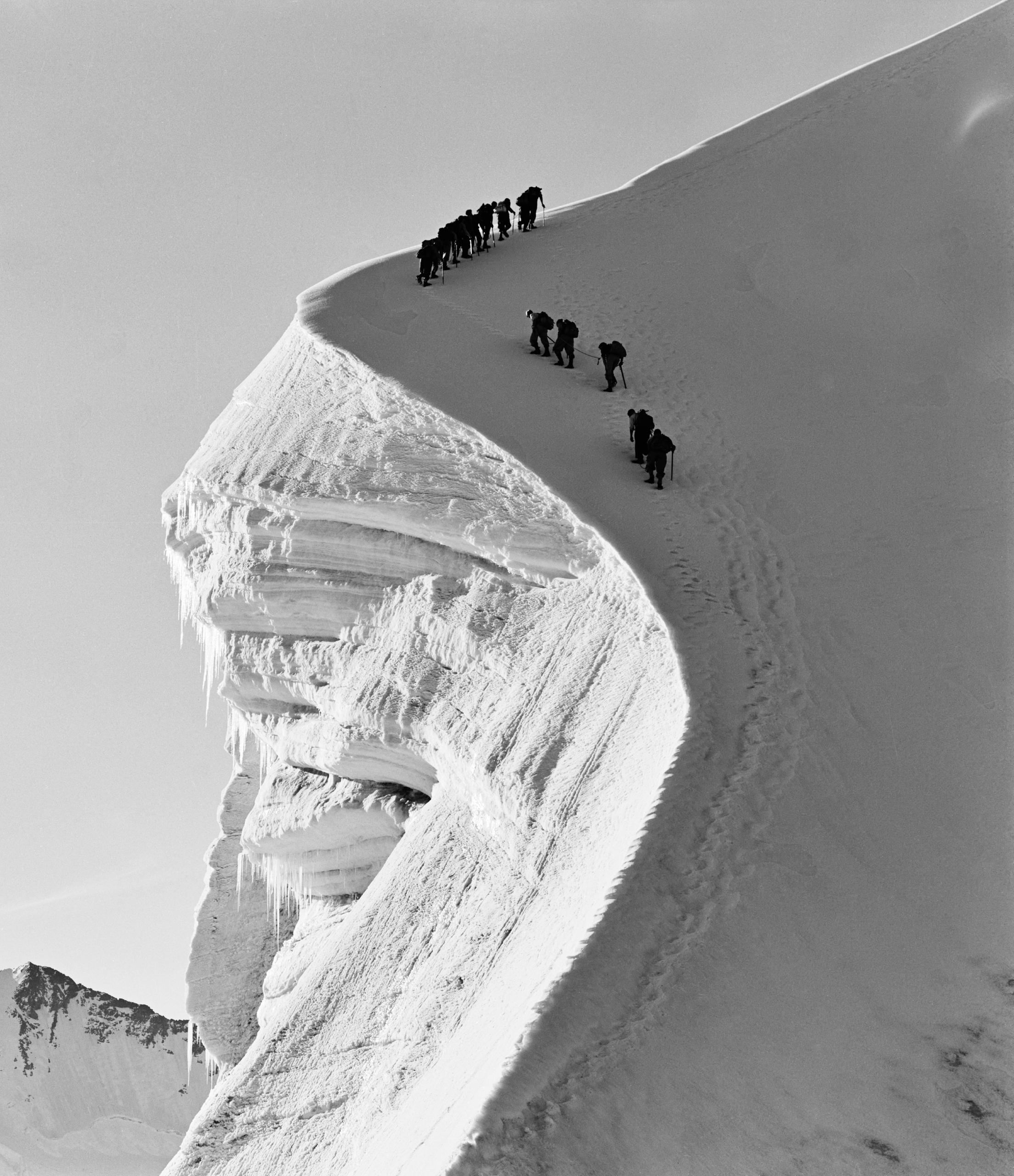صورة بالأبيض والأسود لمجموعة تسلق مترابطة بالحبال في مرتفعات جبلية