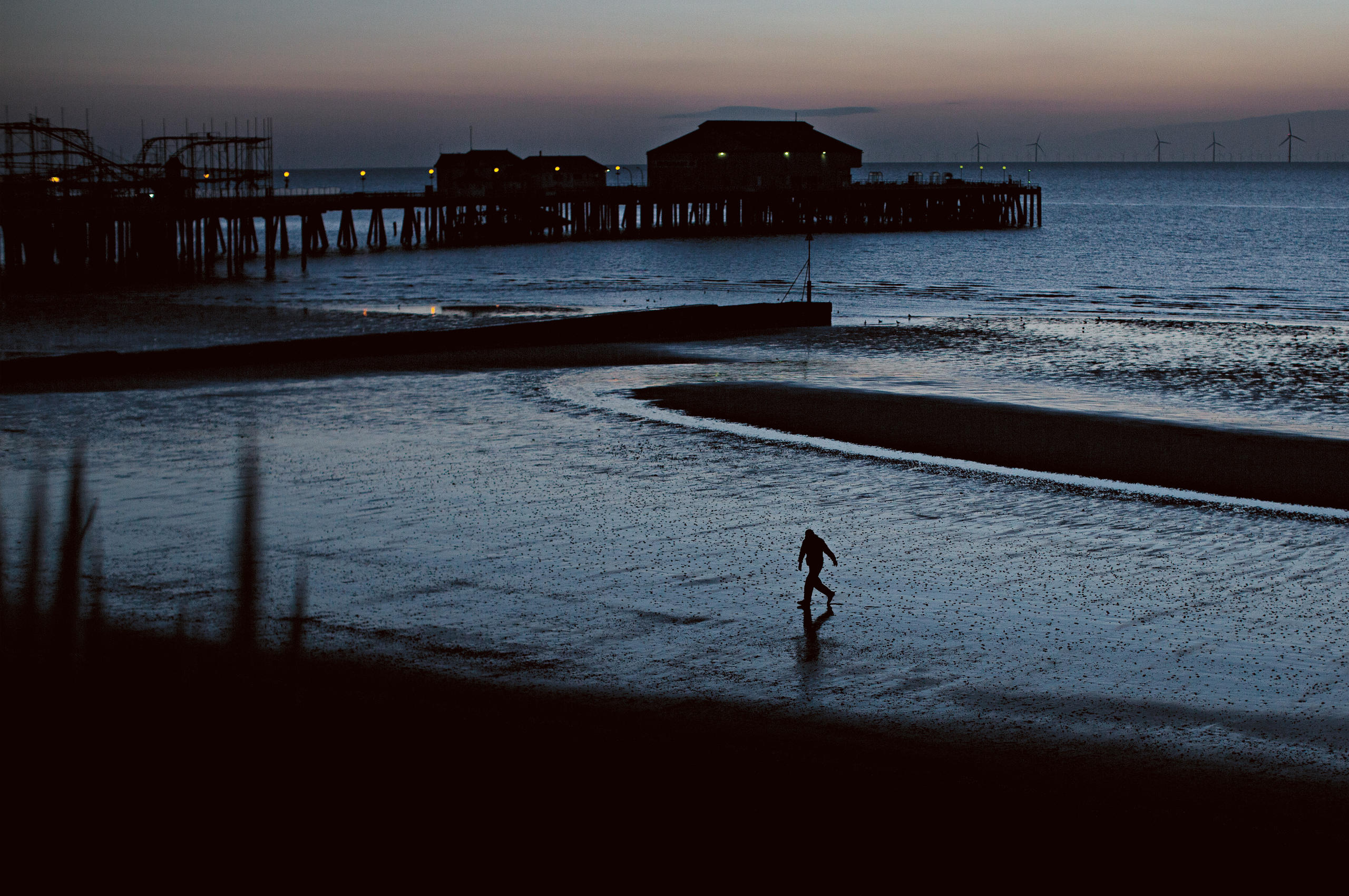 Crepúsculo, un hombre en una playa solitaria