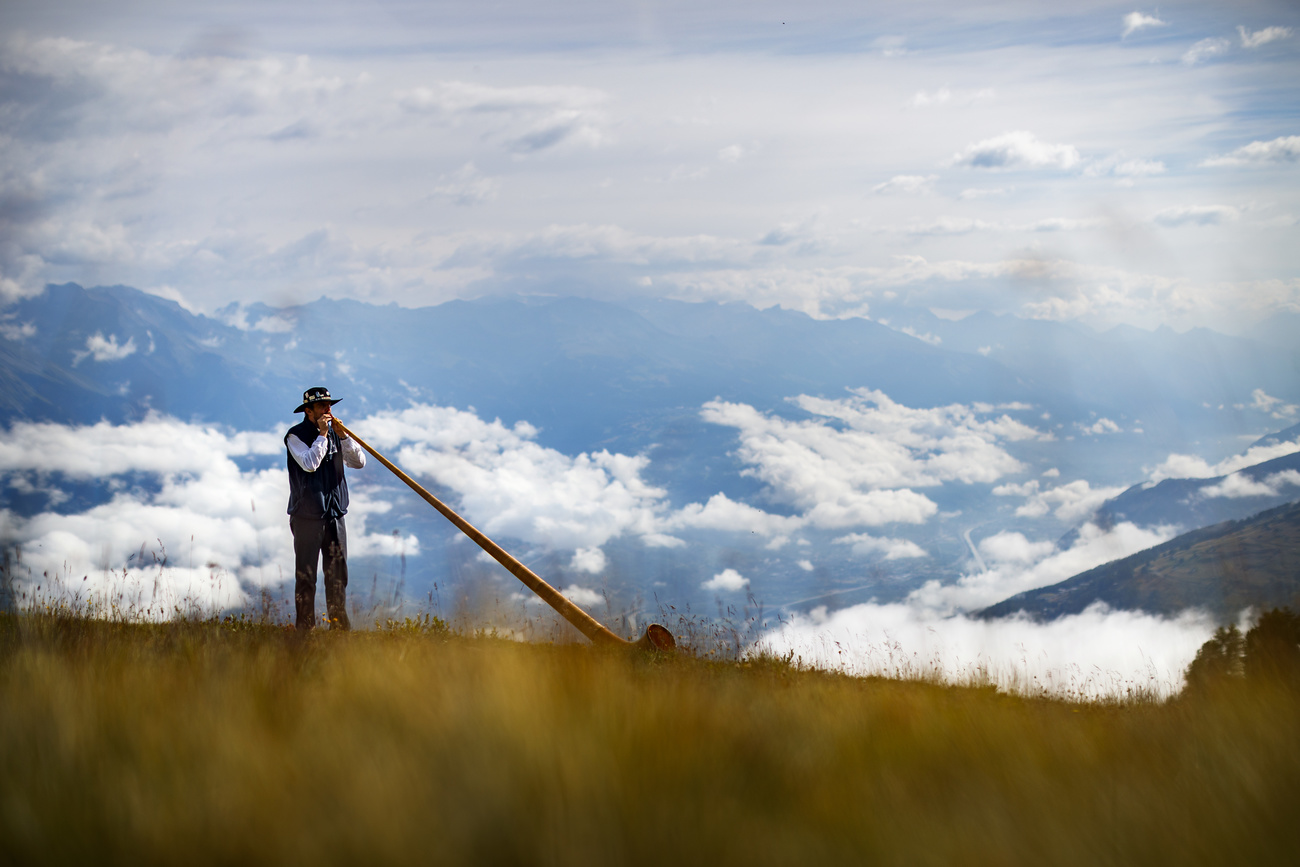 Uomo che suona corno delle su sfondo di paesaggio alpino