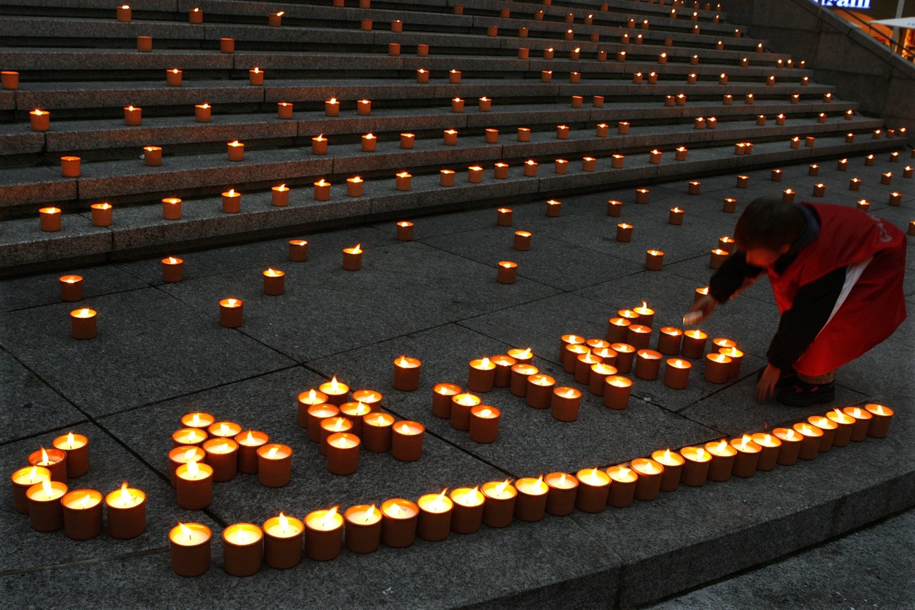 La scritta Caritas fatta con delle candele accese.