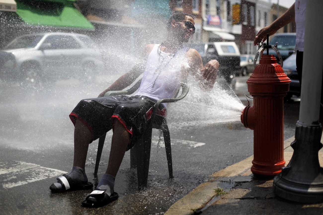 Homme assis aspergé d eau à une borne hydrante.