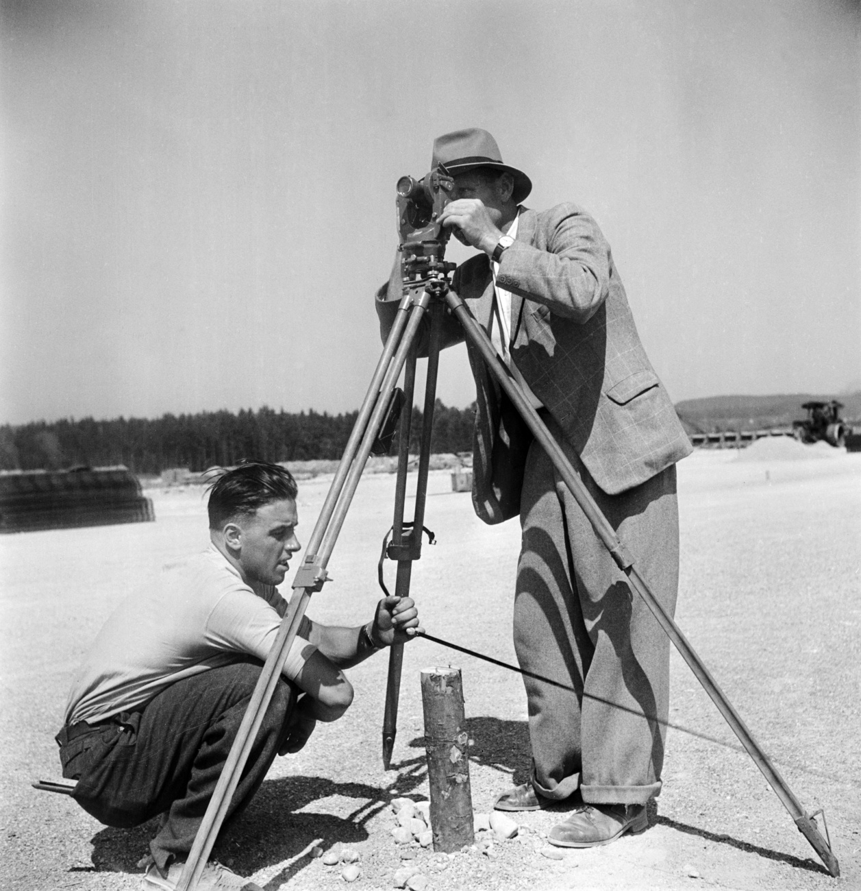 un uomo guarda attraverso un apparecchio di misurazione su un treppiede