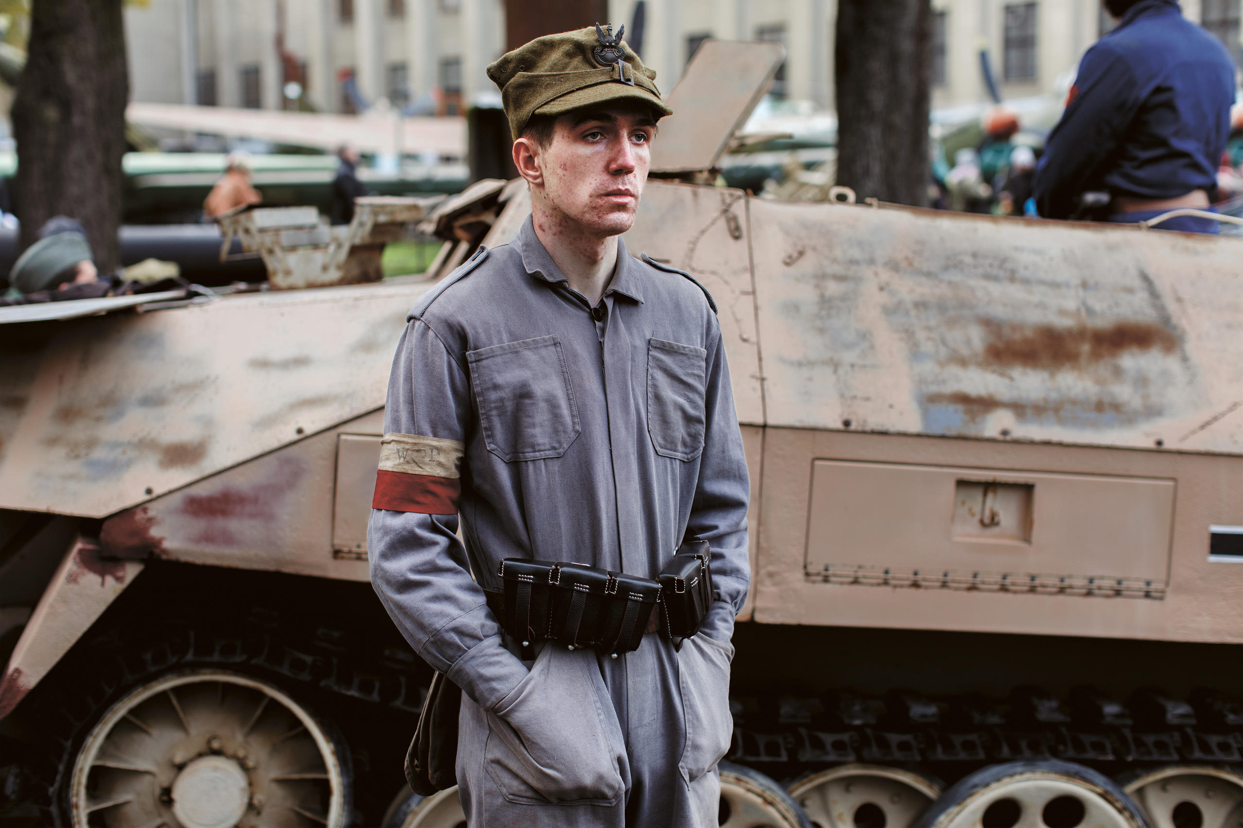 Joven con uniforme delante de un tanque militar