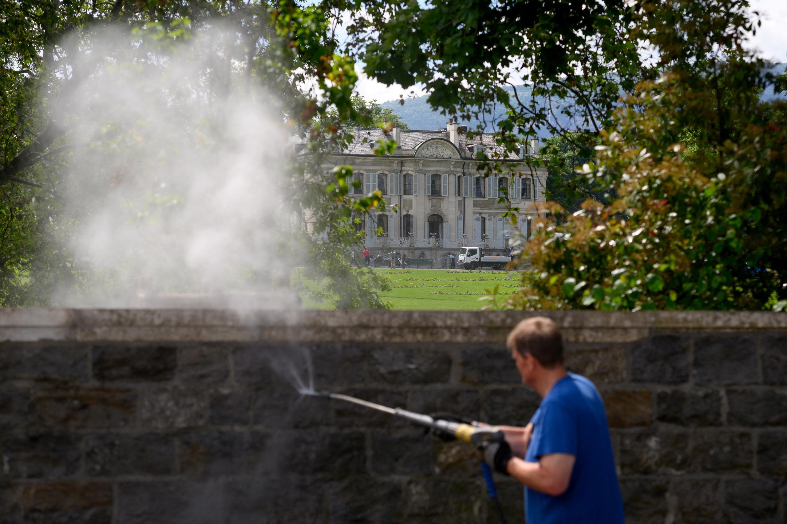 A man uses a pressure washer to clean the low wall