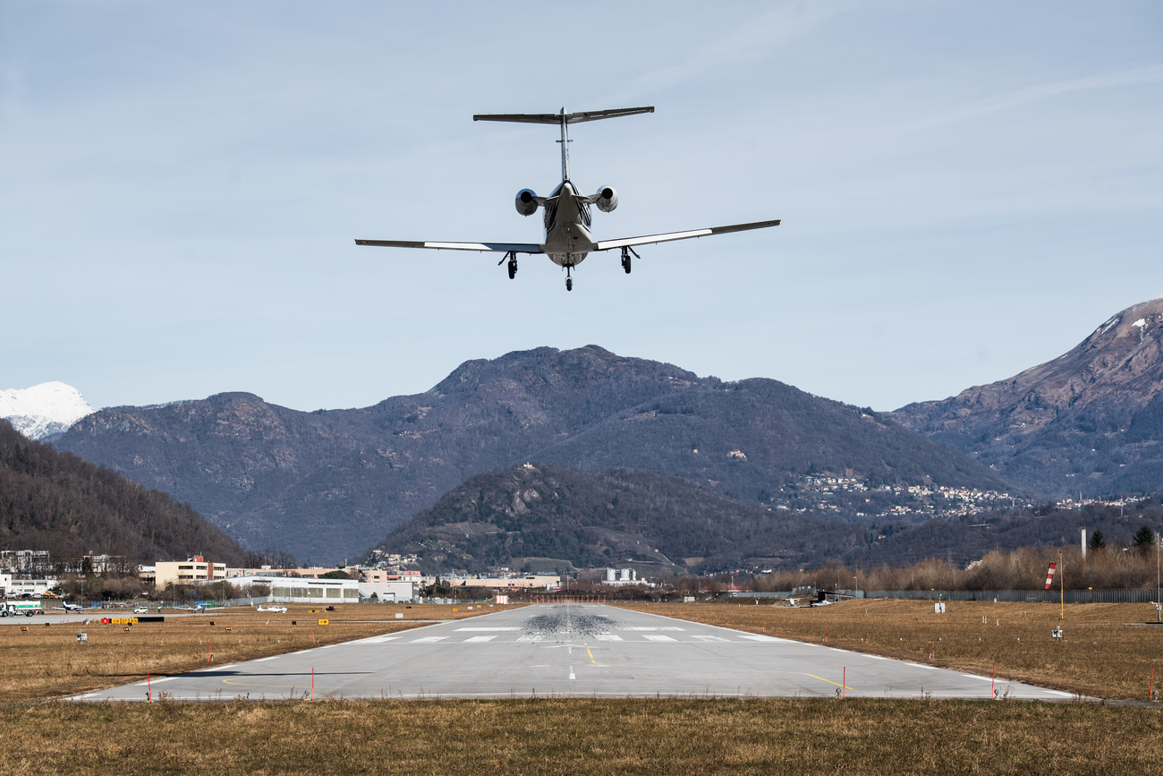 Aereo che sta atterrando su una pista in sottofondo le montagne intorno a Lugano