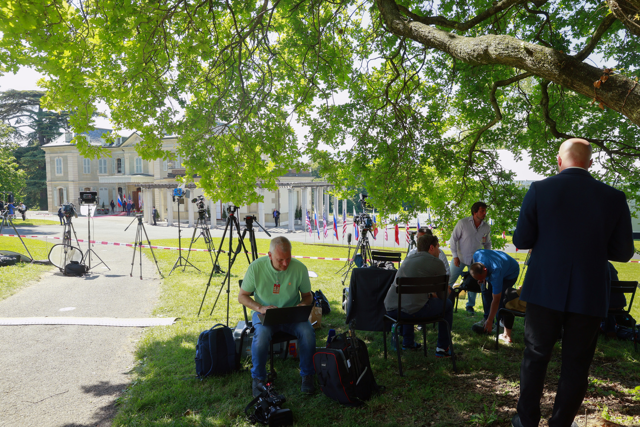 Journaliste devant une villa dans un parc.
