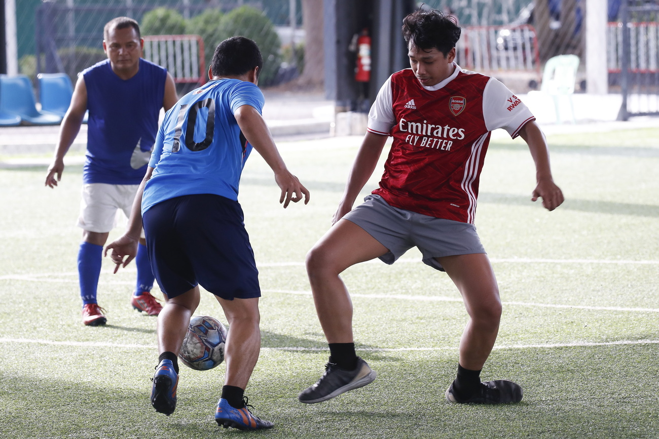 in primo piano due uomini che giocano a calcio, in secondo piano un terzo giocatore che li ossserva